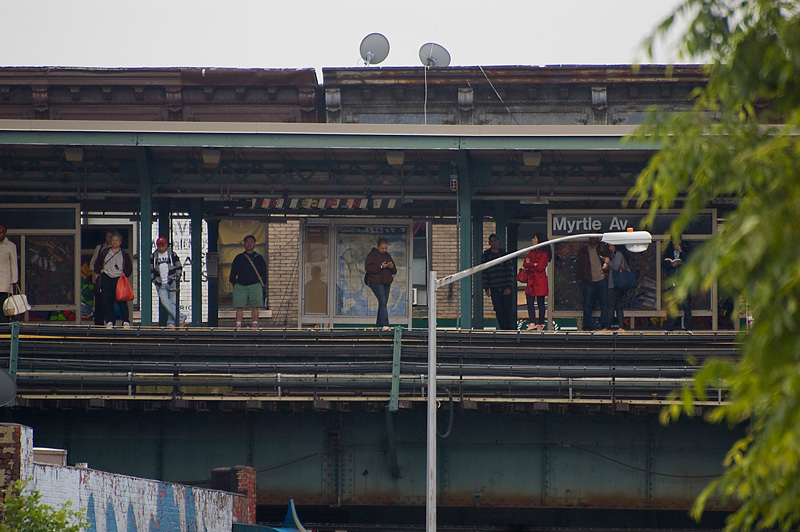 People waiting on an elevated train platform.