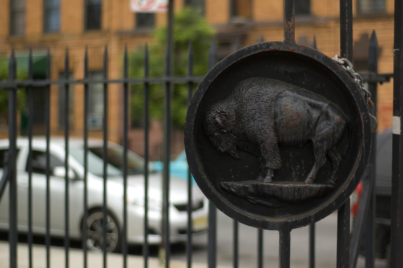 A large black medallion with a buffalo, on a gate.
