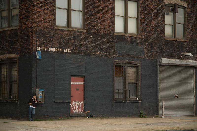 A woman on a pay phone at a corner building.