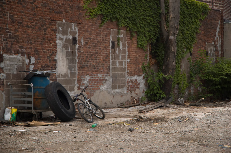 An empty yard with a bike and a large truck tire.