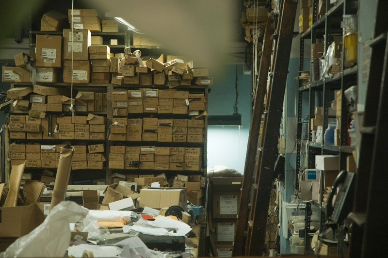 A cluttered desk, packed shelves, and ladders.