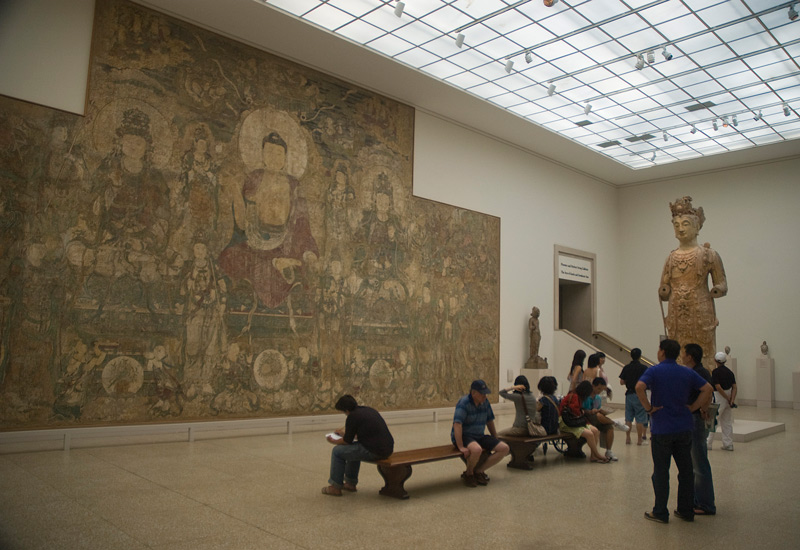 A large museum gallery with a huge tapestry.