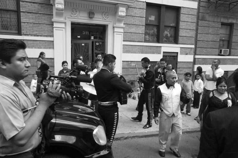 A mariachi band on a sidewalk, with a gathering crowd.