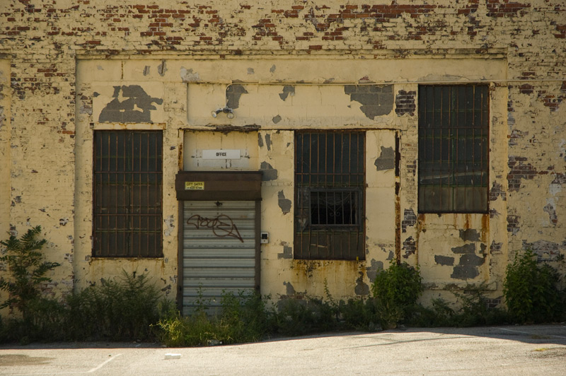 Secured door, barred windows, peeling paint.