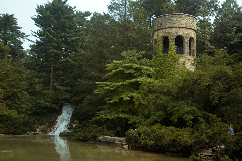 A round tower and waterfall around a large pond.