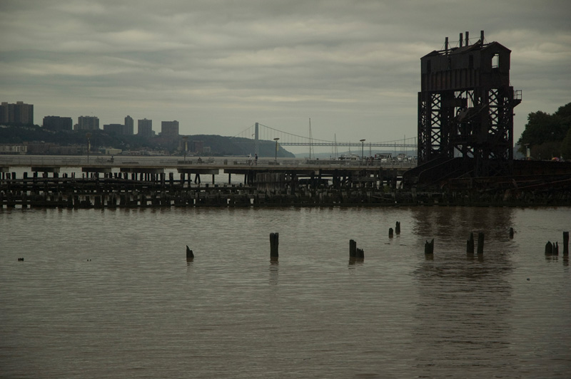 An old railroad gantry, with a bridge in the background.