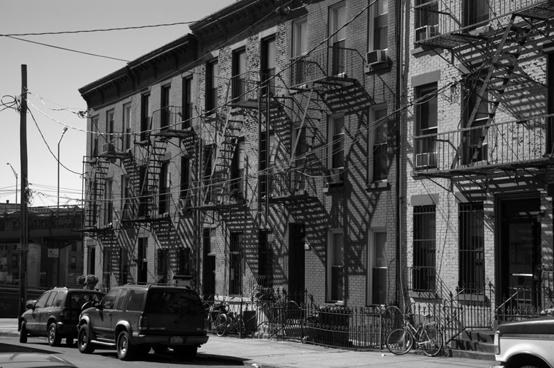 Fire escapes and shadows form diamonds on rowhouses