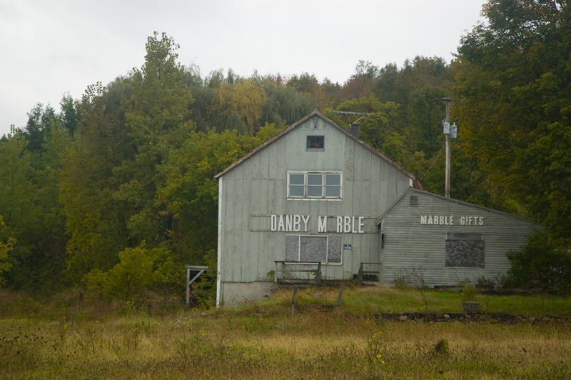 A boarded-up wood building advertising Danby Marble gifts