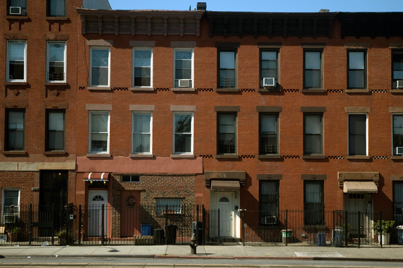 Rowhouses on a vacant street in harsh sunlight