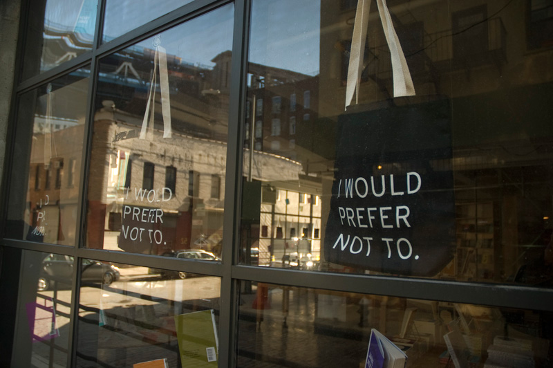 Cloth shopping bags in a bookstore's window, with a famous line from Bartleby the Scrivener