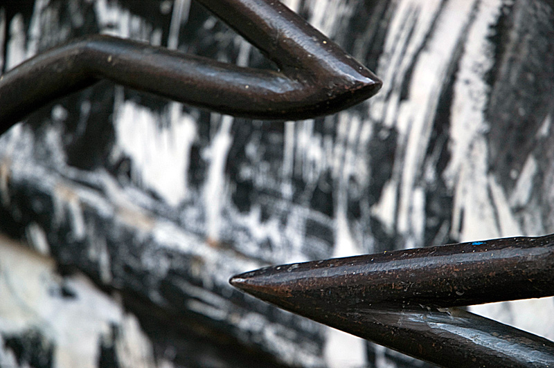 Angular points of a gate, with street art behind them.