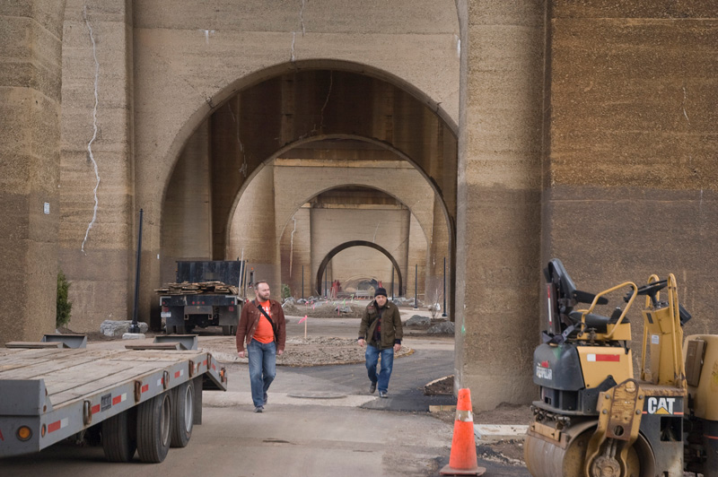 Two men walking between construction machinery.