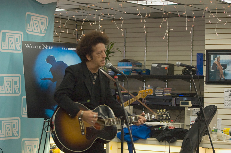 A man with a guitar, singing into a microphone.