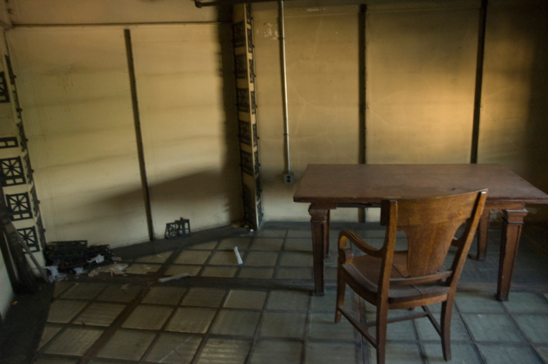 A wooden desk chair and a table in an empty room.