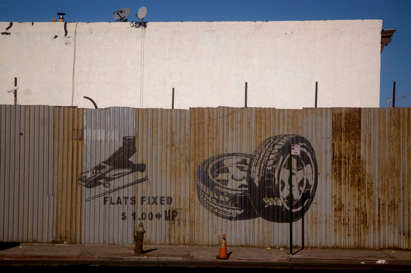 A crude sign on a corrugated metal fence advertising tire repair.