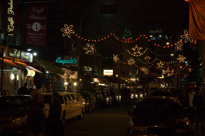 A dark street, with holiday lights and lights from restaurants.
