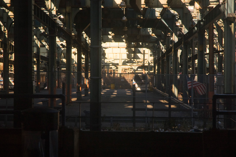 A parking lot covered by shadows from train tracks.