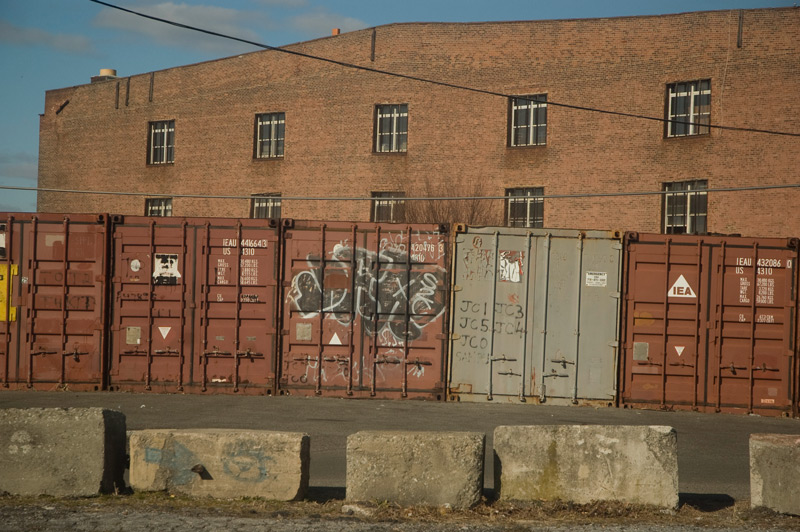 Abandoned shipping containers and an old brick building.