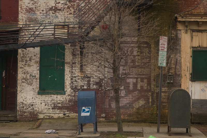 A ghost sign peeks out through white paint on a bubilding.