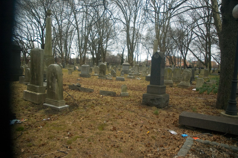 Tombstones in a cemetery with bare trees.