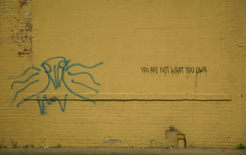 A message on a wall reads 'You Are Not What You Own.'
