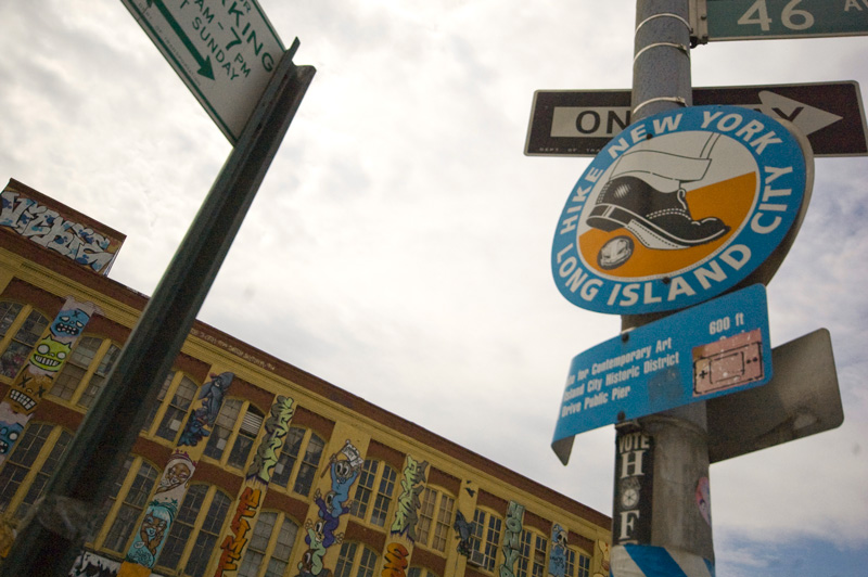 A sign promoting hiking, in front of a graffiti-covered building