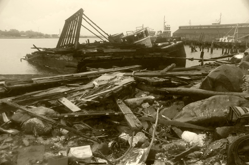 An abandoned tugboat leans against debris