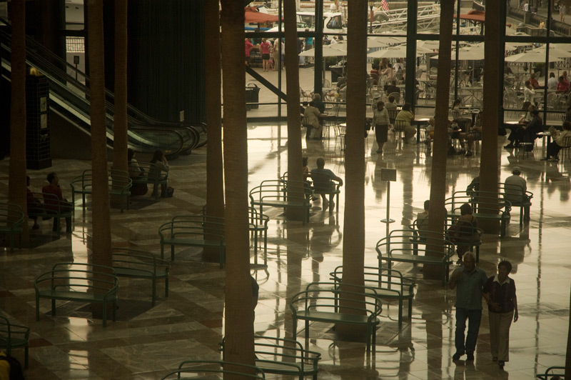 People and benches on a polished floor, with light streaming in