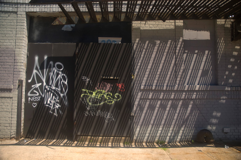 A wall, streaked with shadows from a fire escape