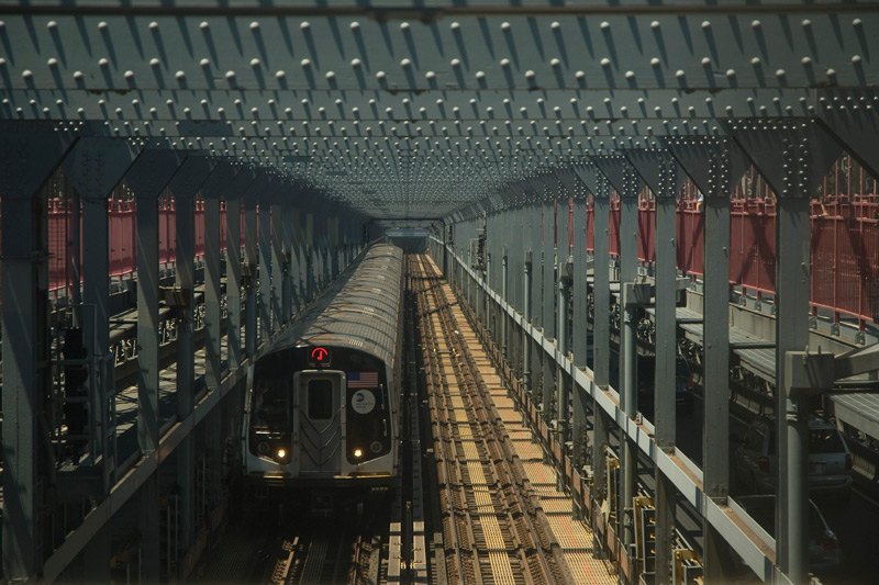 A train on the center tracks of a steel bridge.