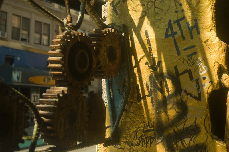 A sculpture of gears and bent metal at a building entrance.