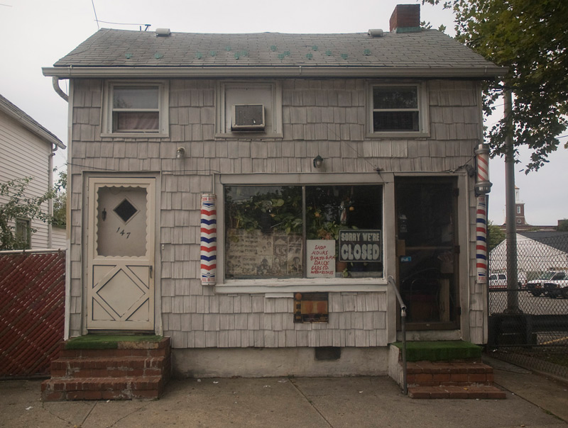 A barber shop with a 'closed' sign in its window.