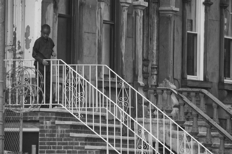 A child looks over his home's stair railing.