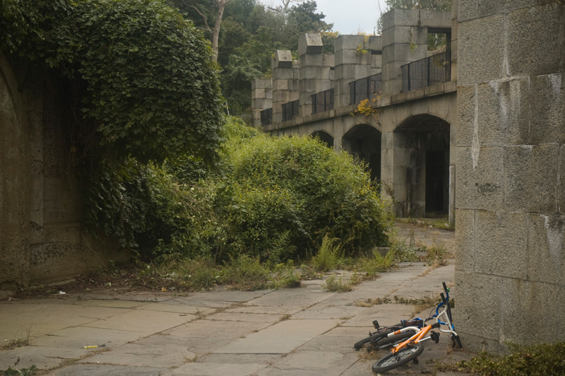 Two bikes at the base of a stone wall.