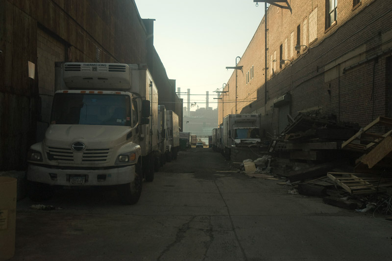 A truck and a smokestacks visible in gap between two buildings