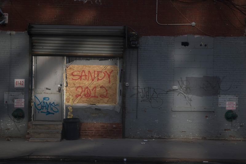 Plywood in a window with a sign about Hurricane Sandy