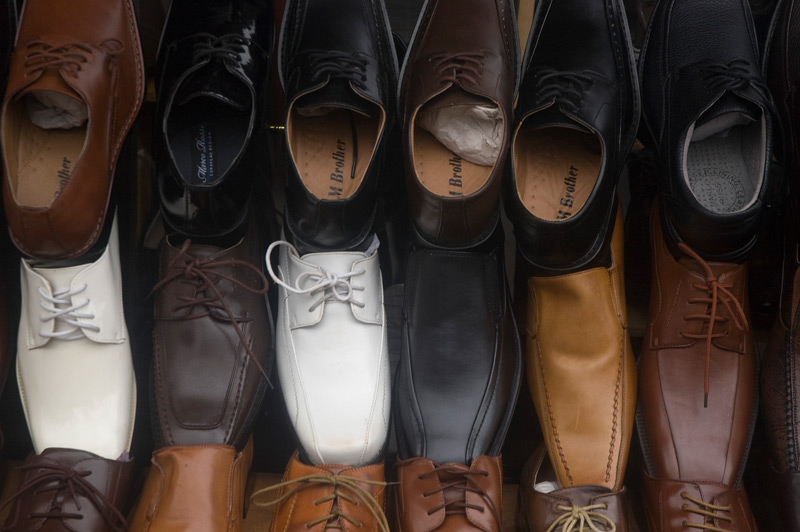 A rack of white, brown, and black shoes outside a store