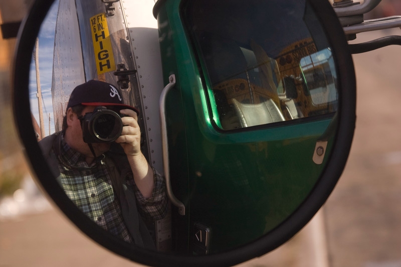 Photographer self-portrait through truck side view mirror.
