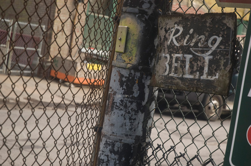A hand painted sign by a gate says 'Ring Bell.'