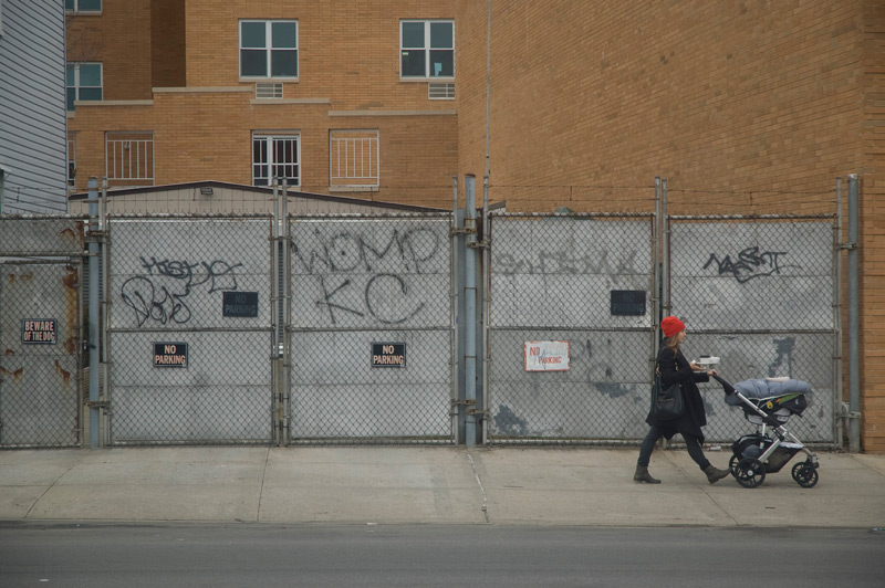 A woman pushes a stroller past a gate