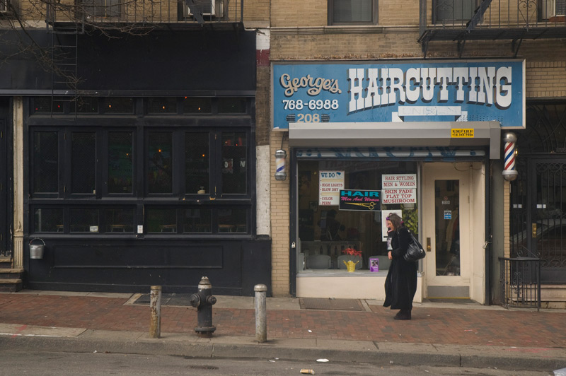 A woman walks past a barber shop