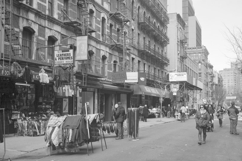 A pedestrian mall with clothing racks and passersby