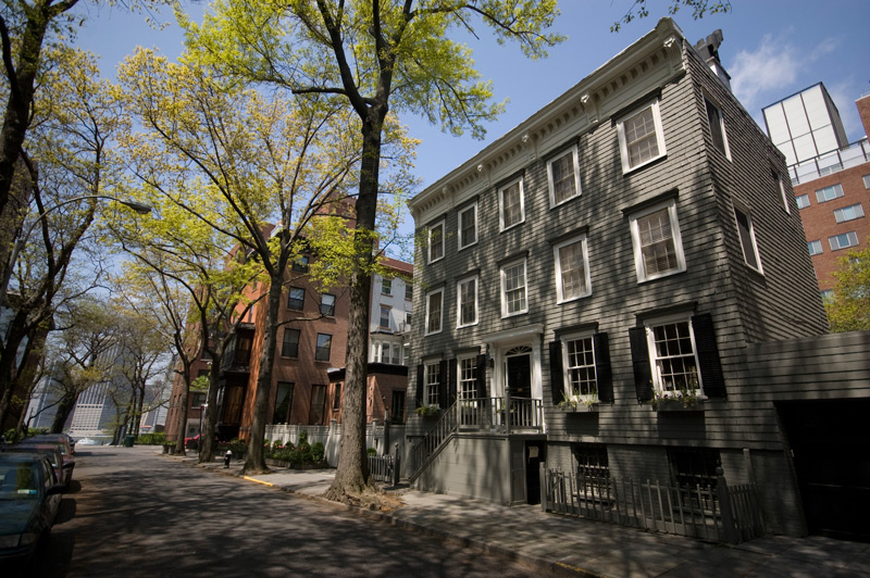 A wooden house on a tree-lined street