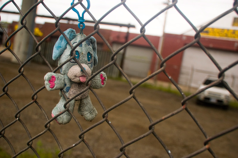 A small, dirty toy hanging on a fence