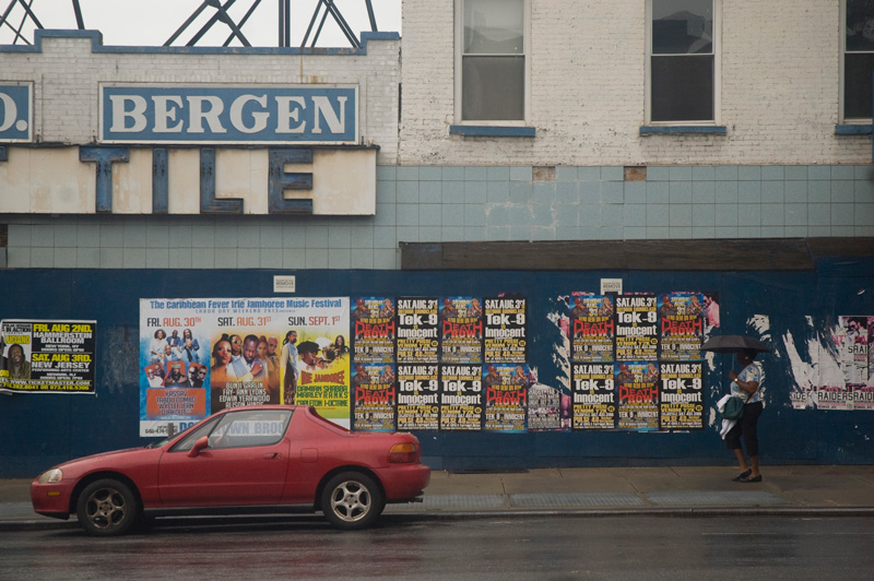 A pedestrian and a car in front of an abandoned tile store.