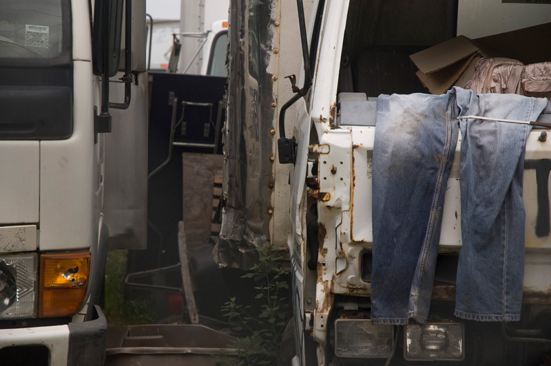 Blue jeans drying over a wrecked vehicle in a junk yard.