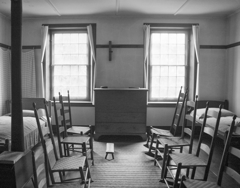 A dresser in a room with beds and chairs.