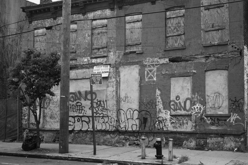 Boarded-up, graffiti covered shell of a building.