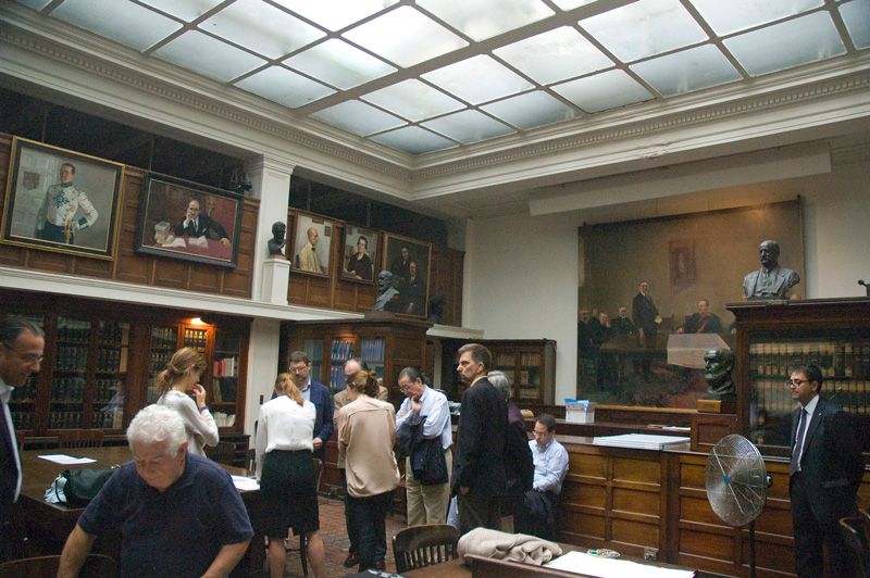 People in a room of books and portraits.