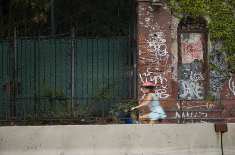 A bike rider going past graffiti.